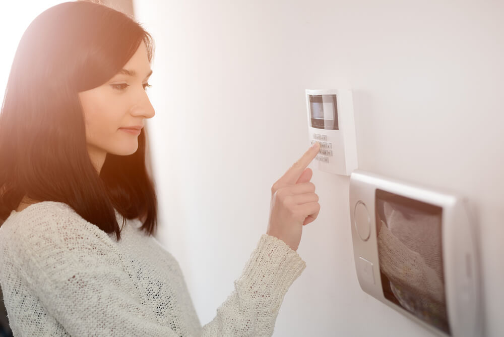 A young woman turning on alarm system which may be a factor that affects home and contents premium