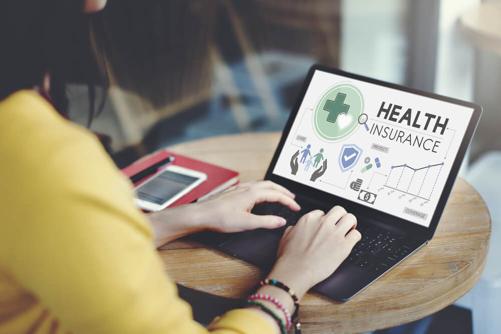 A young single looking at health insurance on a laptop