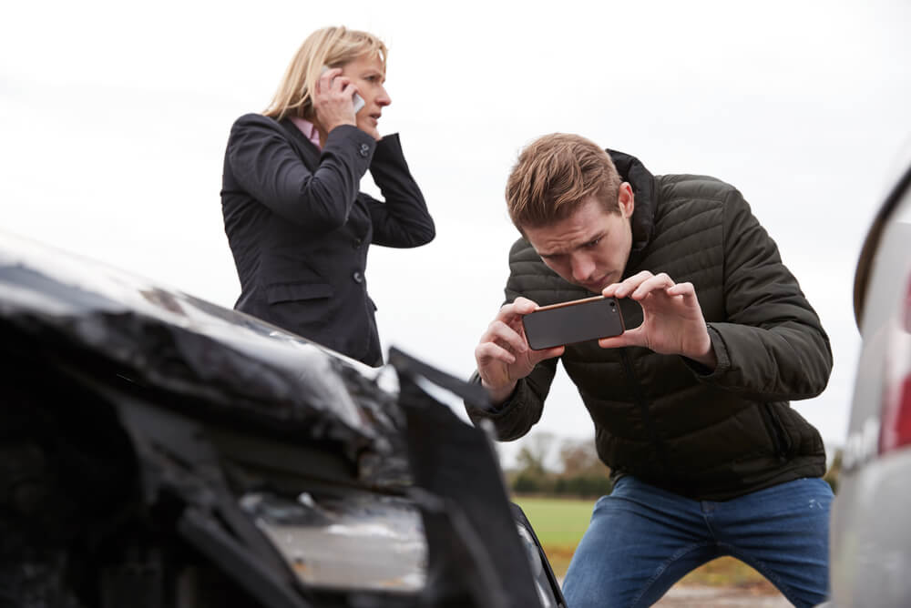 Man taking a photo for his car insurance claim.