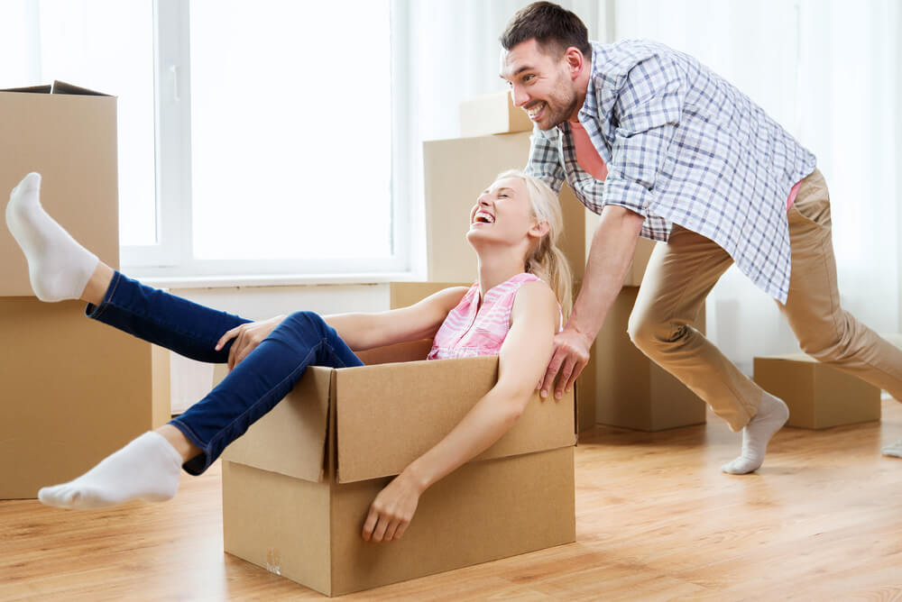 a man pushing a woman around in a cardboard box