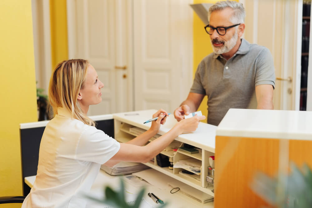 older man paying for healthcare service through extras cover