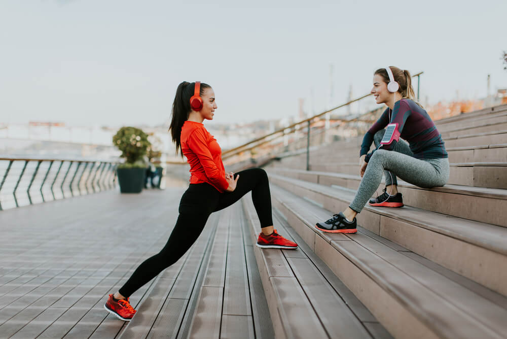 two young women exercising on steps with headphones on