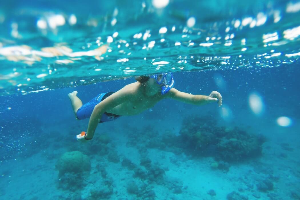 a man snorkelling over the reef at Lifou Island, New Caledonia