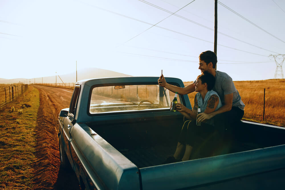 a couple takes a selfie sitting in the back of their ute tray
